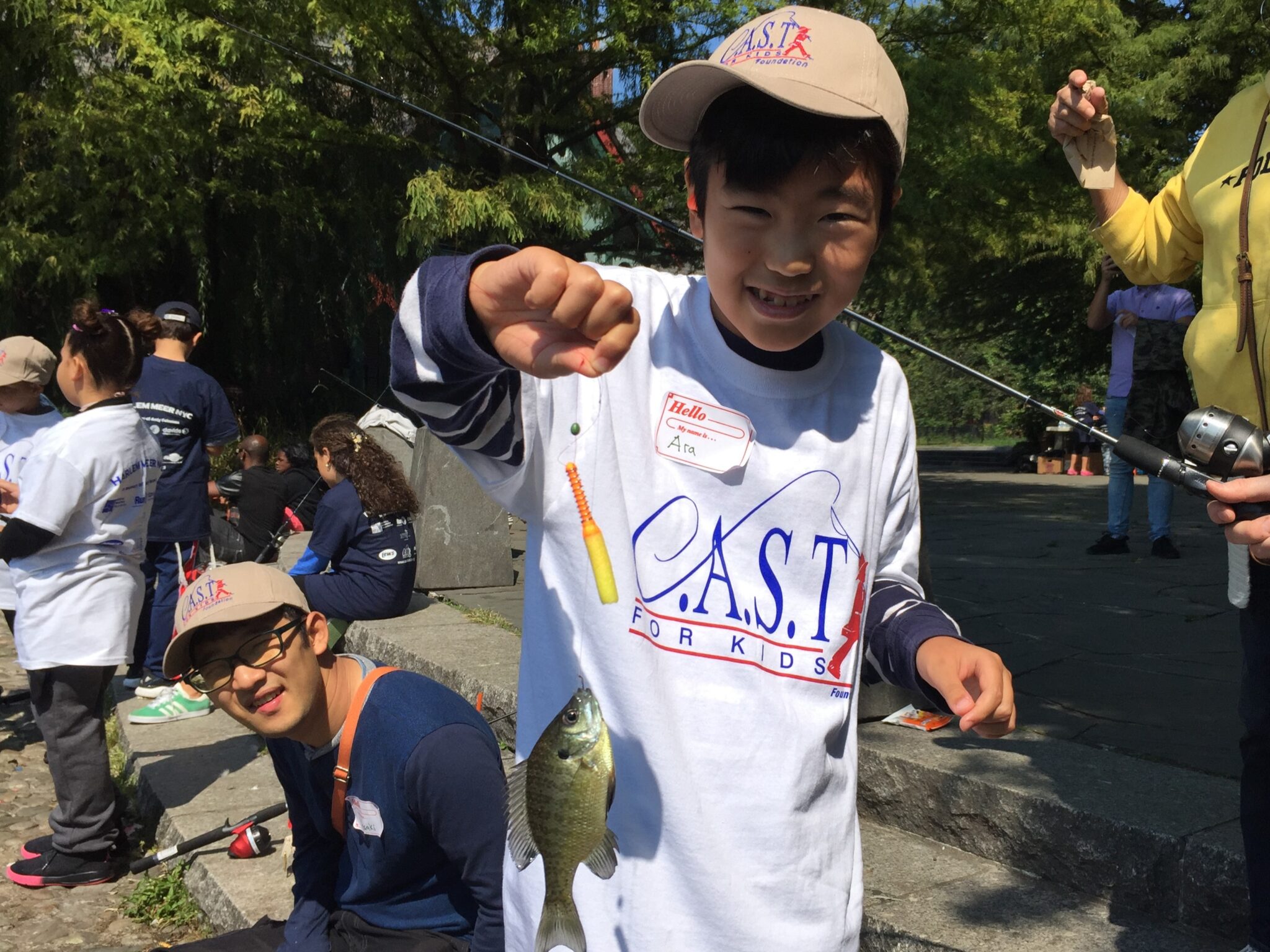 two participants holding fish at central lake pond