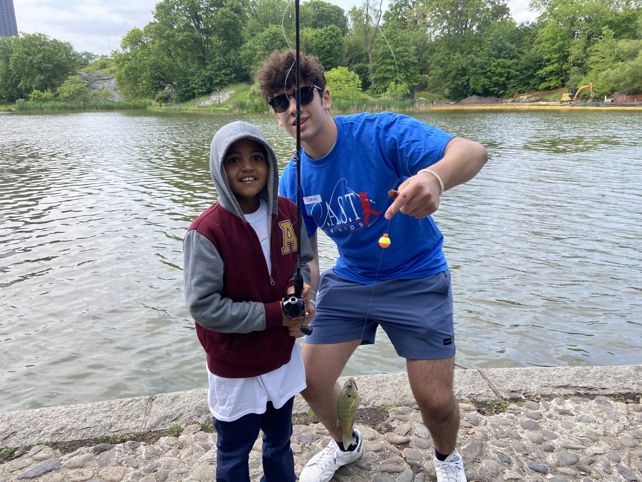 participant holding fish at central lake pond