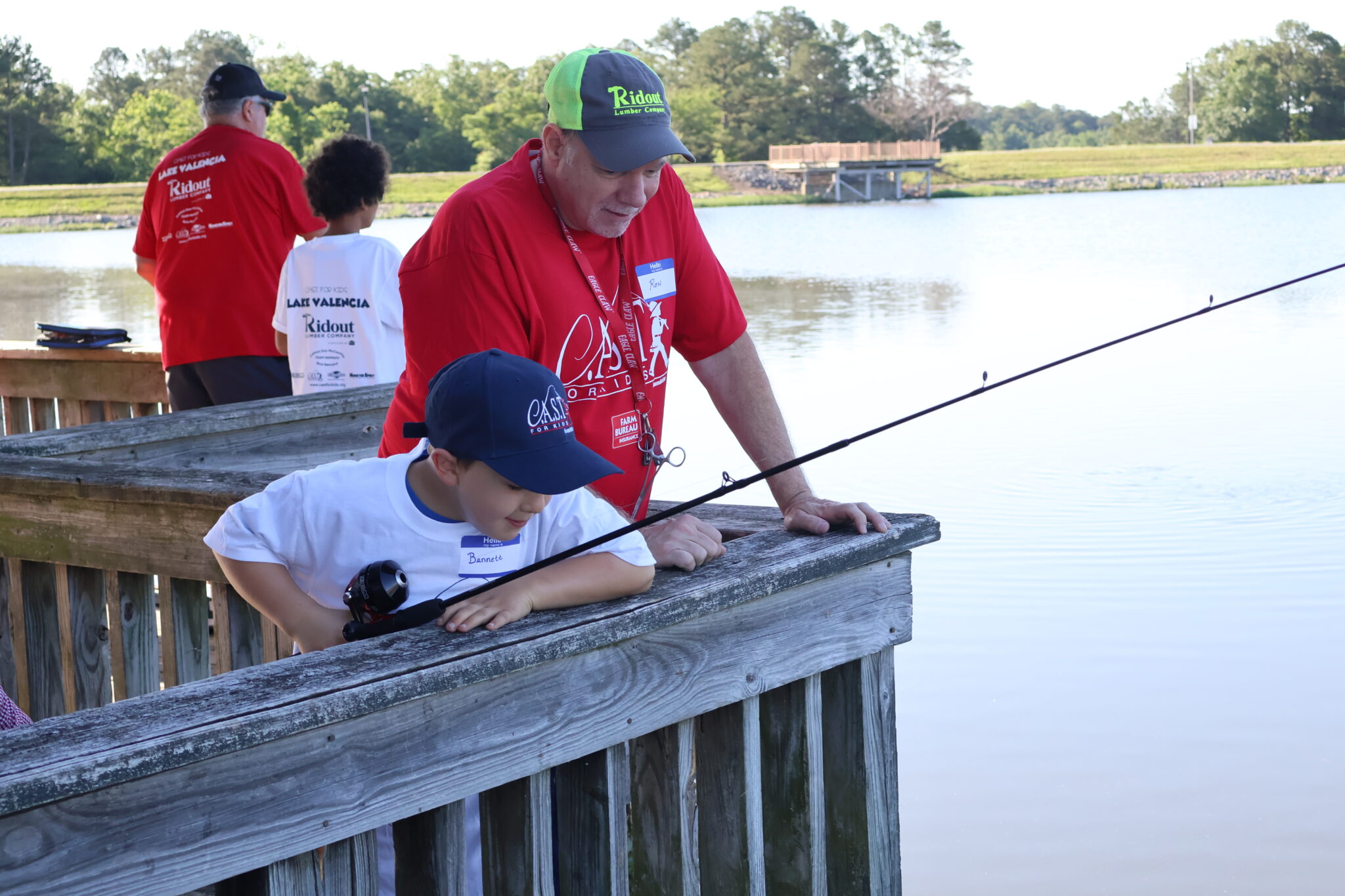 2024 Lake Valencia Volunteer coaching child volunteer on a deck fishing with a child