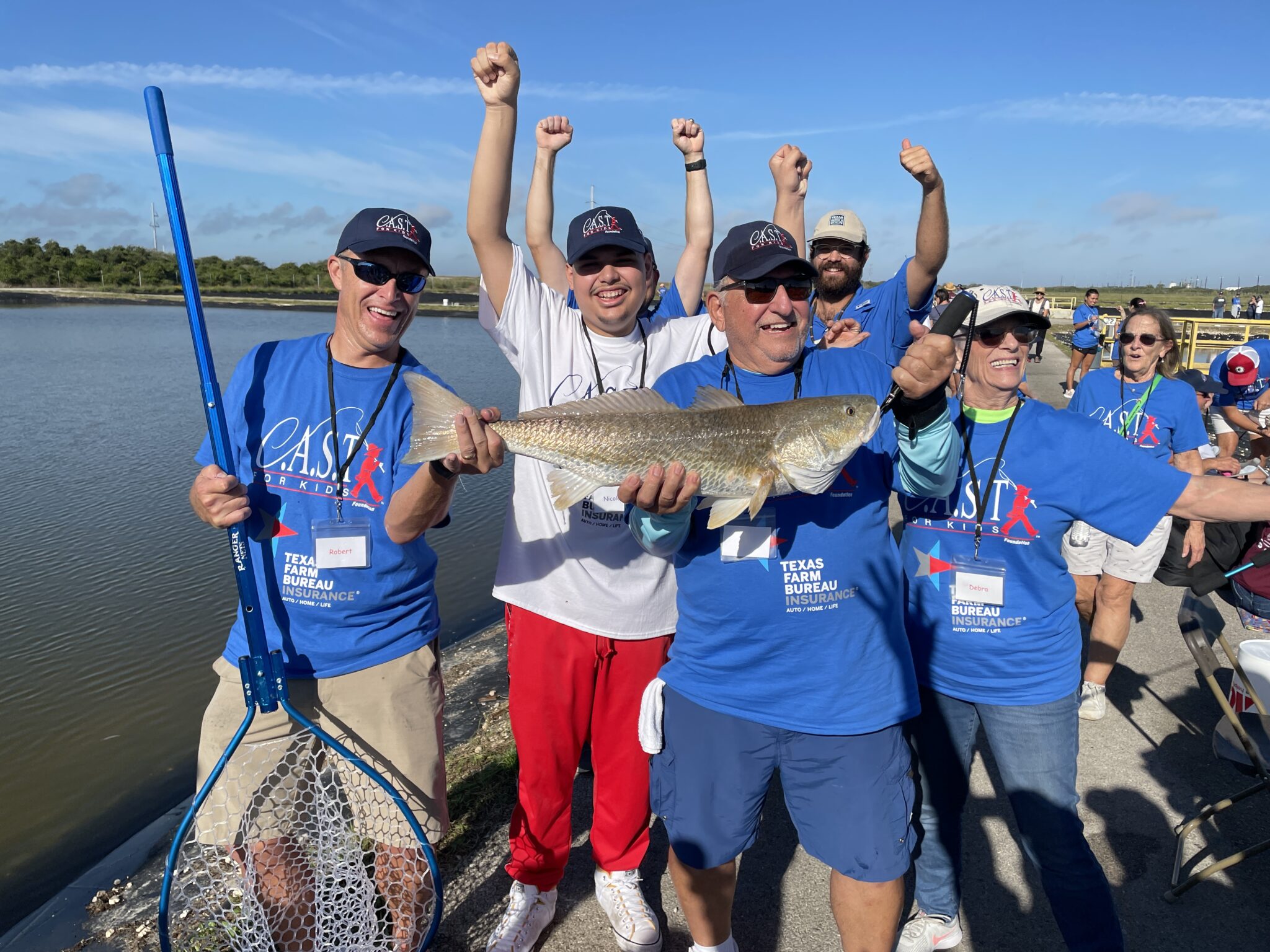 Homepage Impacting Lives volunteers with a caught fish with young people