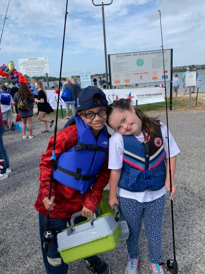 two children holding fishing poles and smiling