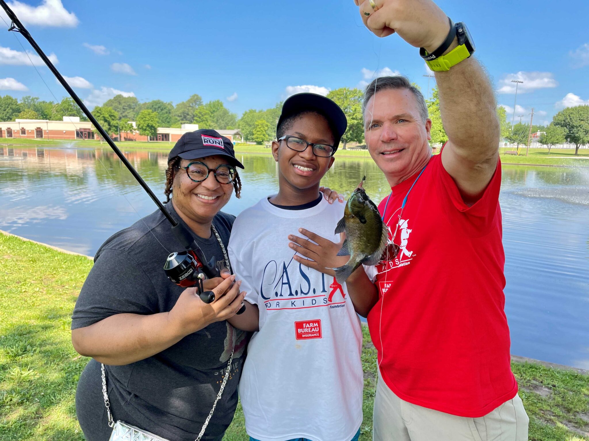 Arkansas Farm Bureau (1) CAST for Kids fishing participant with volunteers holding a fish
